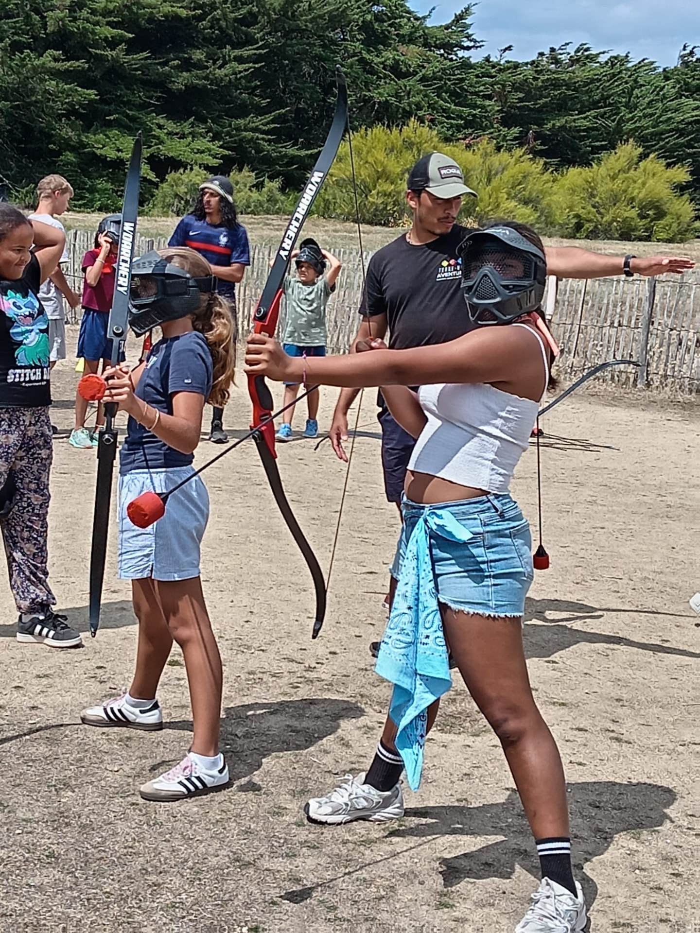 Battle archery : participantes en visée avec arcs et flèches à embout mousse, masqués, encadrés par Terre-Mer Aventure à Penthièvre