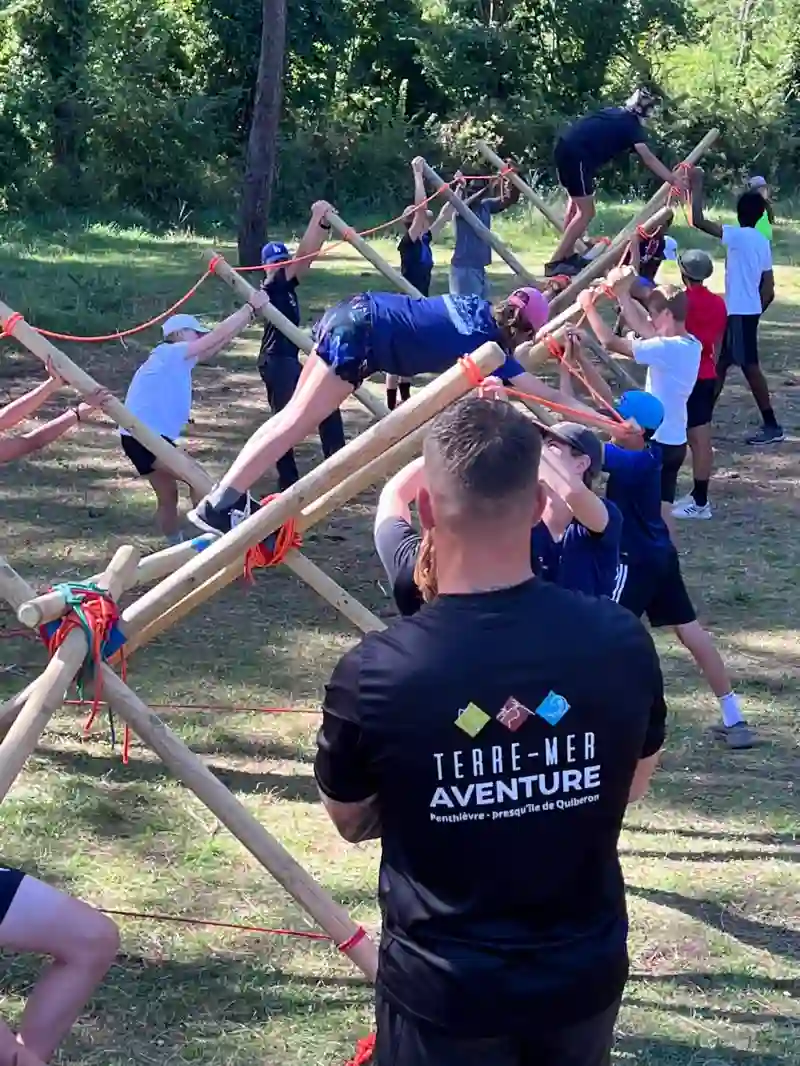 Stage Robinson : groupe construisant un passage à l'aide de perches et cordes en forêt, encadré par Terre-Mer Aventure à Penthièvre