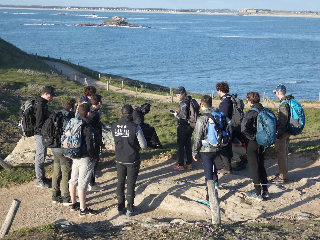Groupe en randonnée sur un sentier côtier avec vue sur la mer et les îles du Morbihan