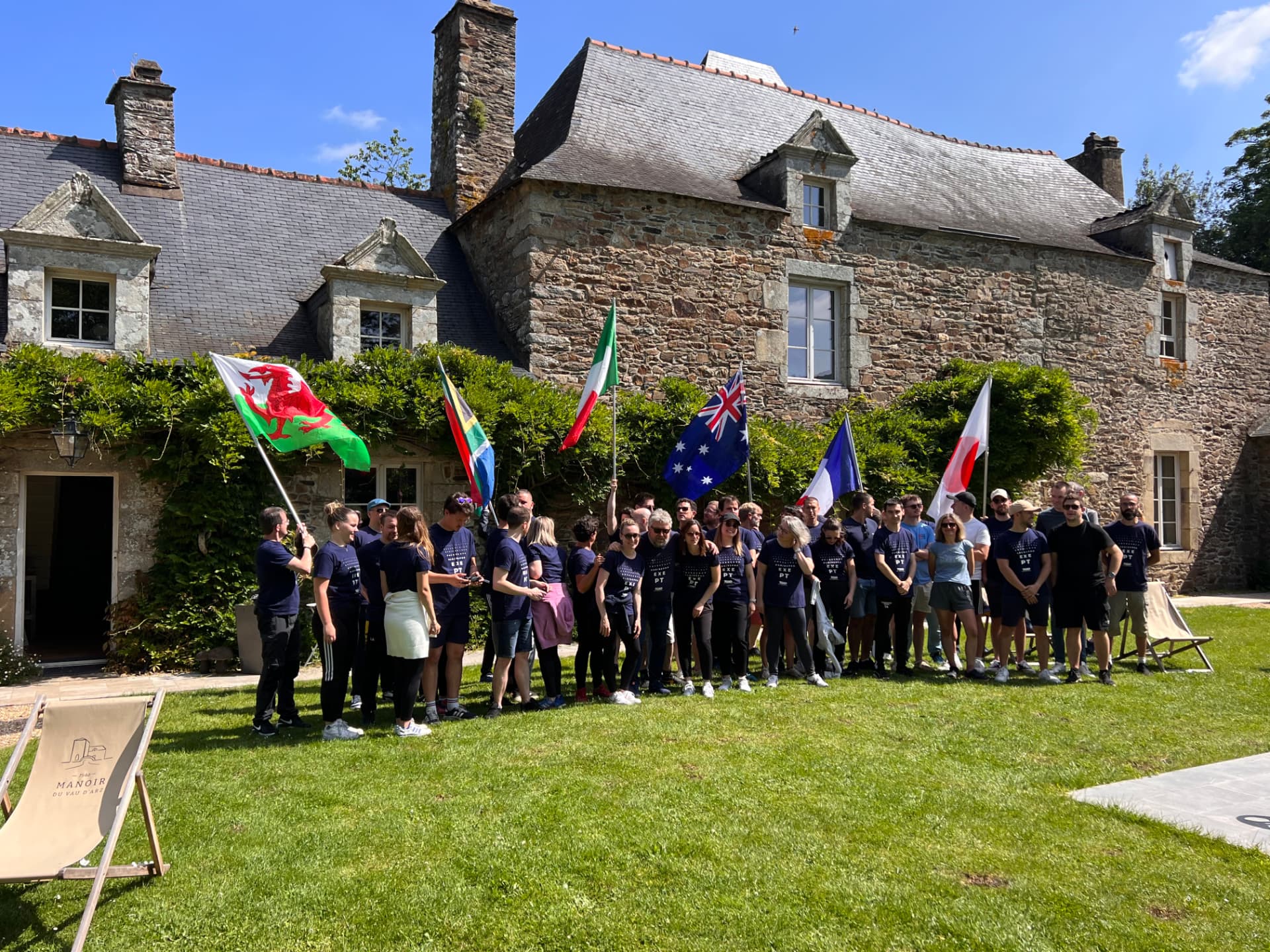 Olympiades : grande photo de groupe avec drapeaux nationaux devant le Manoir du Vau d'Arz, esprit jeux olympiques bretons