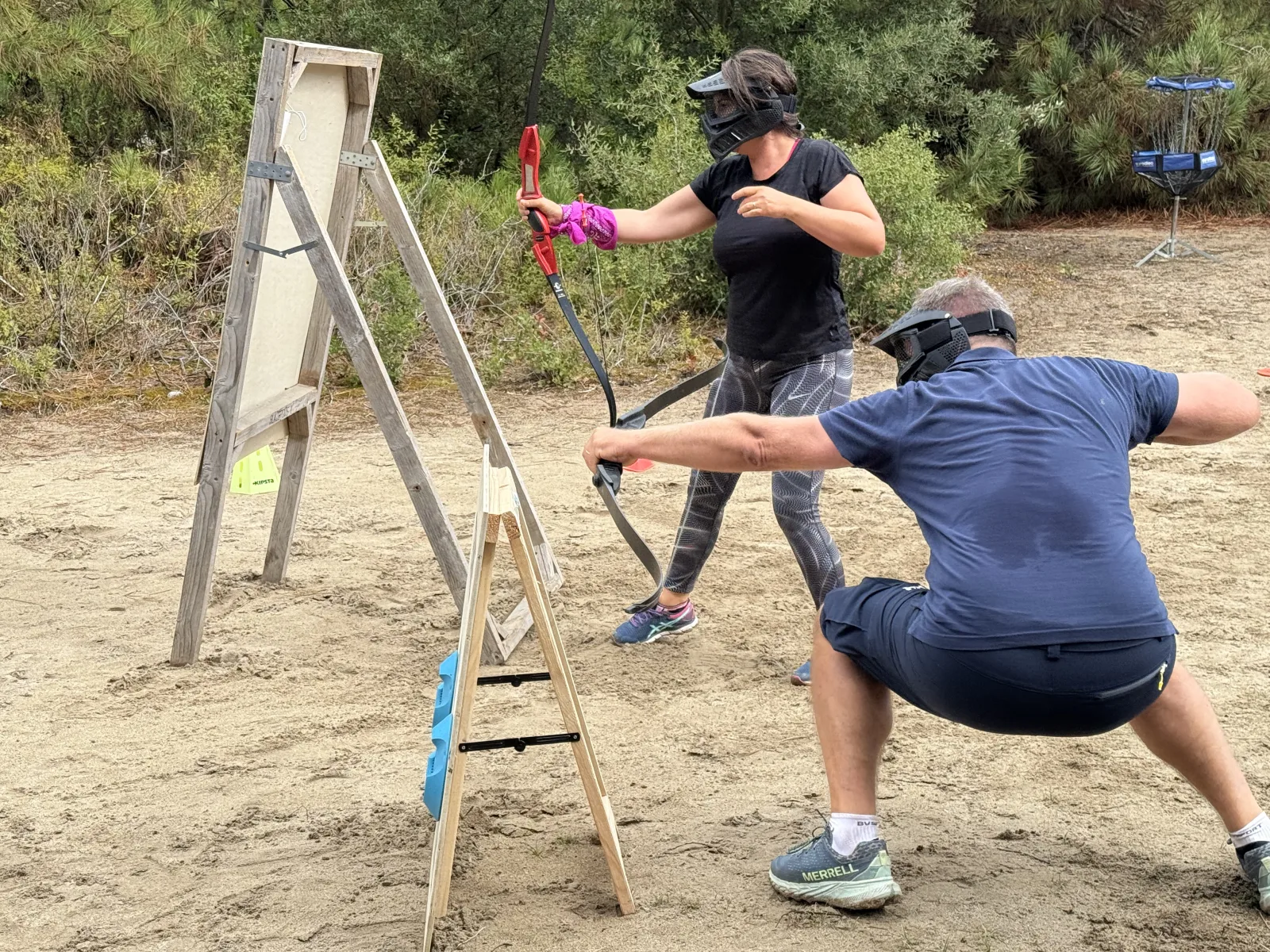 Archery Tag : femme et homme en séance de tir à l'arc avec flèches à embout mousse sur un terrain sablonneux bordé de pins à Quiberon Bretagne Sud