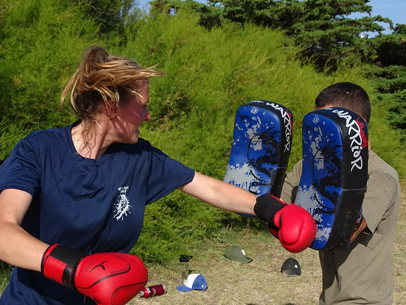 Atelier de boxe en plein air : une participante frappe dans un bouclier tenu par un animateur lors d'un Stage Robinson à Quiberon