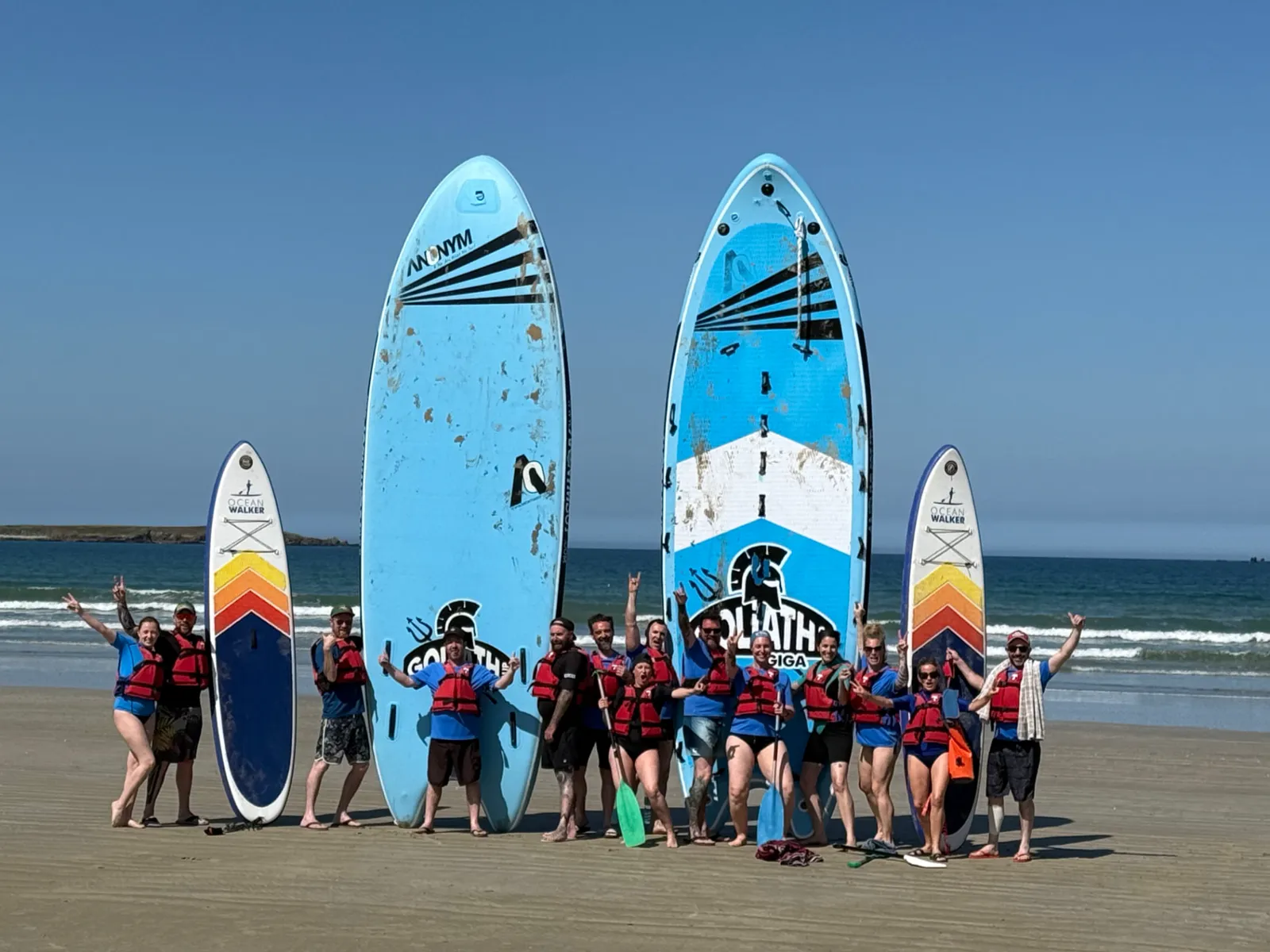 Raft de mer : un groupe de quinze participants en gilets rouges posant avec deux planches de paddle géant Goliath sur la plage de Penthièvre, presqu'île de Quiberon